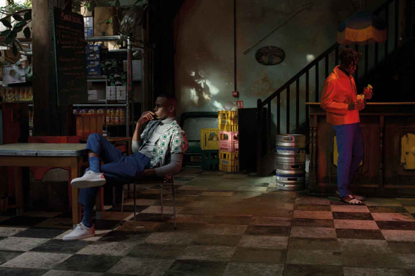 Left, Axel wears: Graphic printed cotton shirt, LAURENCE AIRLINE, grey roll-neck sweater, ICOSPHERE, zipped front over pants in blue cavalry twill cotton, JOHN GALLIANO, trainers, HOUSE OF MONTAGUE, socks, CHAINE ET TRAME. Right, Kirikoo wears: Terracotta lambskin jacket, CARVEN, blue printed cotton trousers, RENOMA, strap sandals, TILLMANN LAUTERBACH