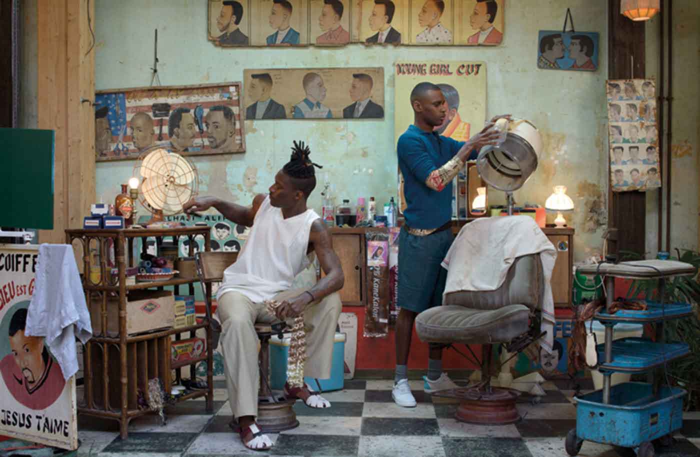 Left, Kirikoo wears: White striped V-neck sleeveless vest and beige cotton Trousers, 22/4, strap sandals, TILLMANN LAUTERBACH. Right, Axel wears: Blue long sleeve polo shirt, ROBERTO COLLINA, gold printed black knitted top, NUUR, cotton bermuda short, FROM BRITTEN, trainers, HOUSE OF MONTAGUE