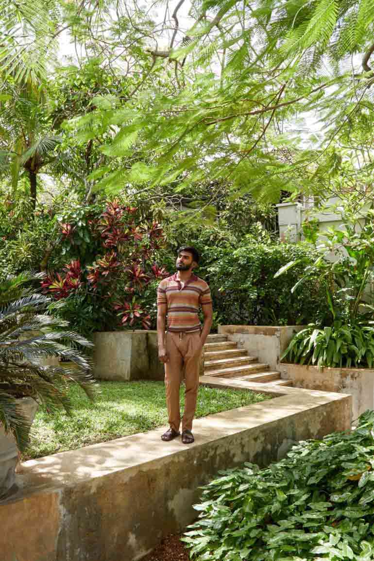 Model wearing flax striped polo shirt and cotton-and-silk trousers with drawstring waist by Corneliani and brown leather 'Chadwick' sandels by Grenson in Galle, Sri Lanka
