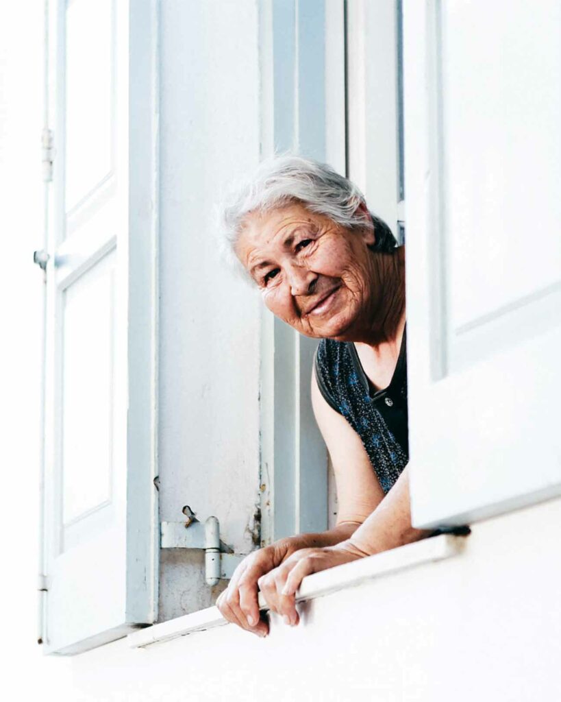 An elderly lady observes local life on the Greek islands