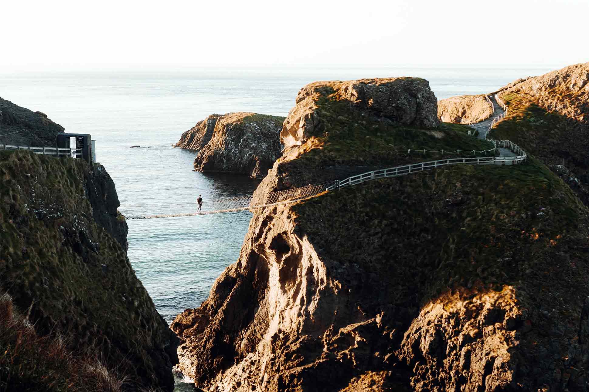 A hiker explores the Carrick-a-Rede Rope Bridge, Northern Ireland