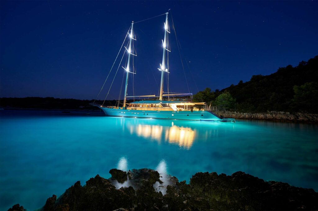 A yacht anchored off a coast at night
