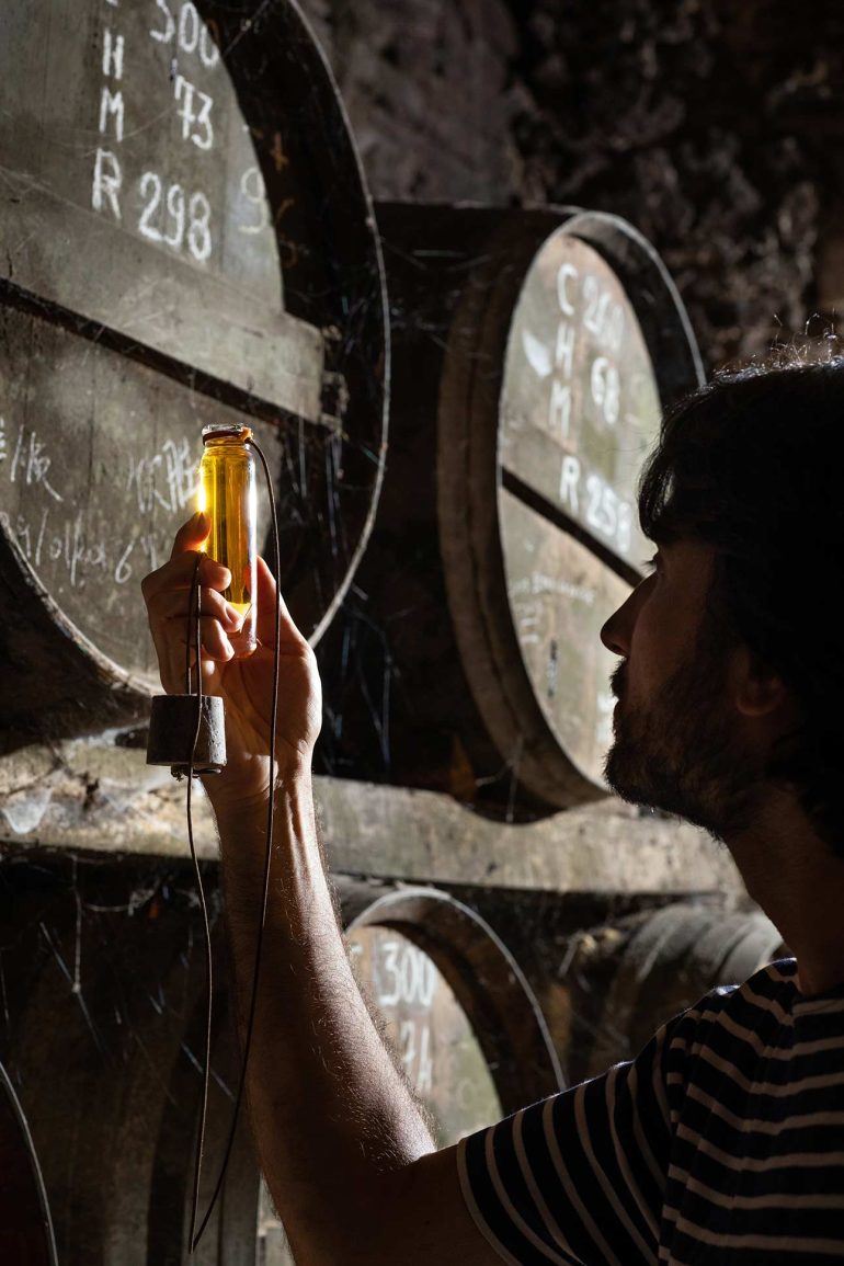 An employee checks the colour of a batch of Bourgoin Cognac in Charente, France