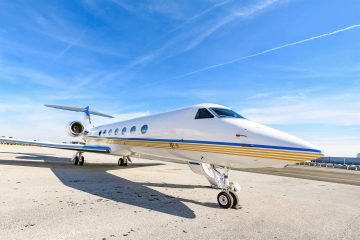 A Gulfstream G550 is parked near a landing strip