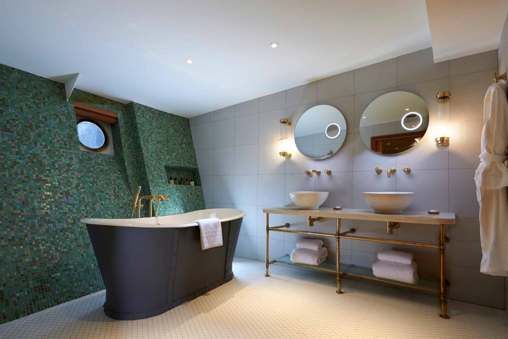 A bathroom with a freestanding bathtub and stylish green tiles at Fingal, Edinburgh, Scotland. 