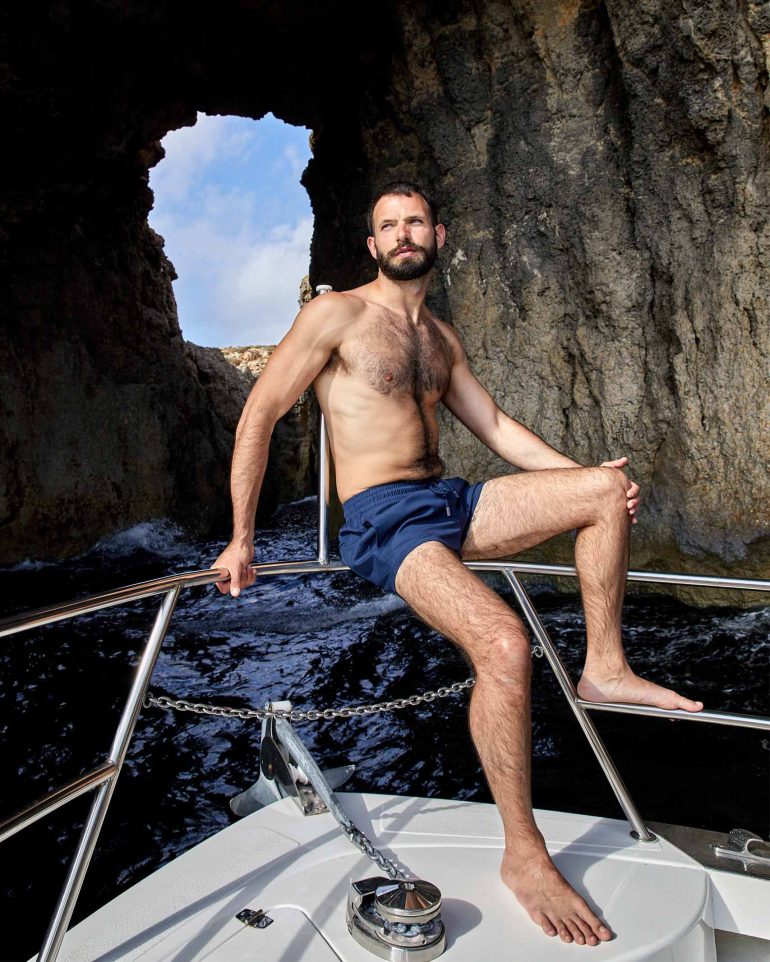 Model sits on the railing of a yacht in Comino, Malta