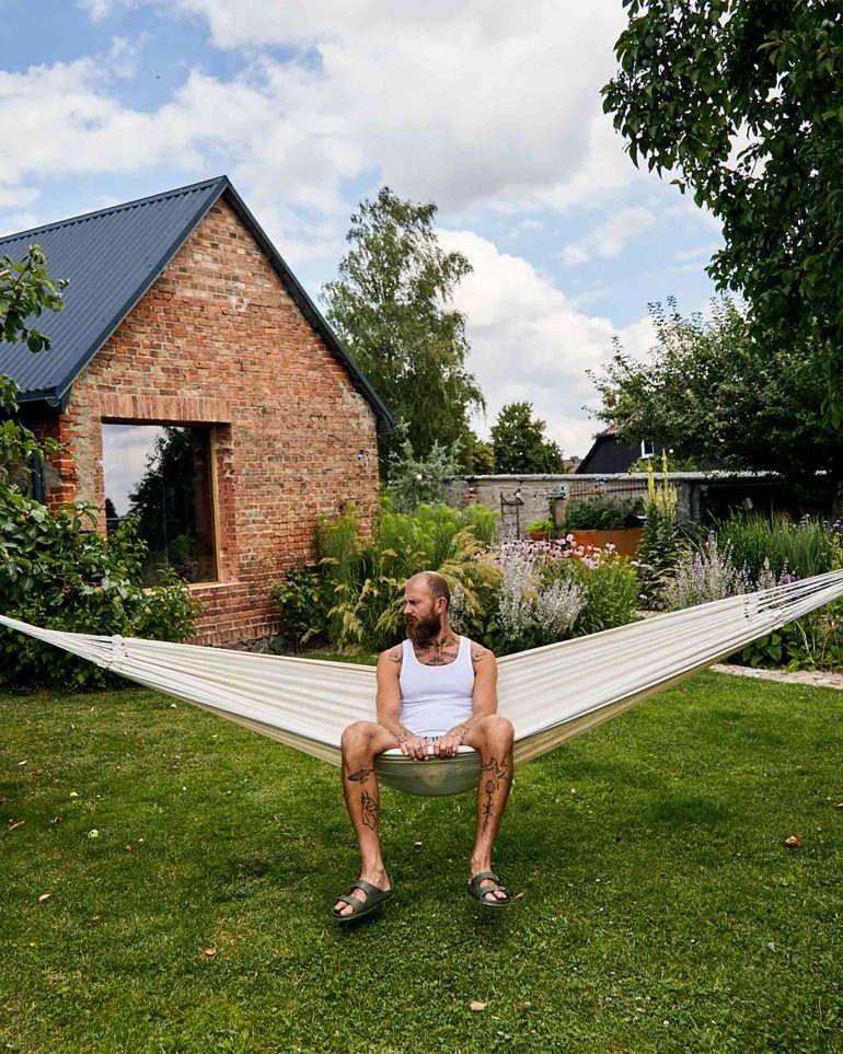 Andreas Zaremba relaxes in a hammock in the garden of Hof Flieht, Uckermark, Germany