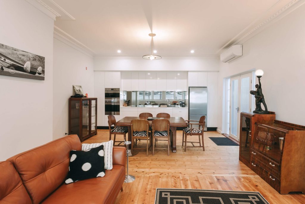A lounge/dining area with wooden chairs and tables at Deco Beach Luxury Apartments, Port Lincoln, Australia