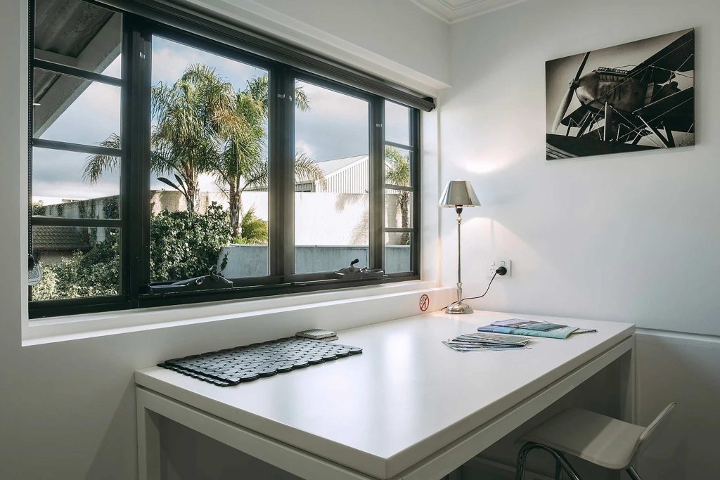 A study area with a large window revealing palm trees