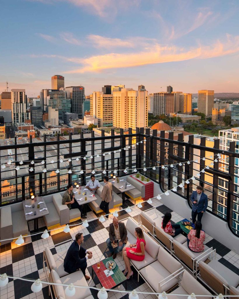 Bustling rooftop bar area with panoramic views of Adelaide.