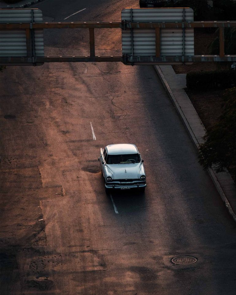A vintage car drives down a street in Cuba