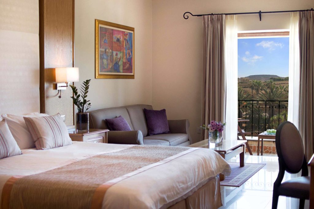 A bright room with a soft colour palate and stunning views of Gozo, Malta