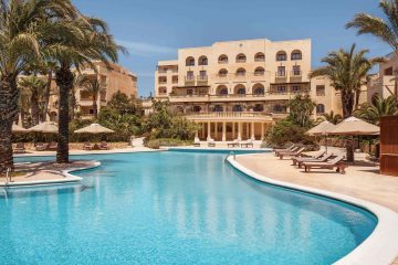 A pool area enclosed by palm trees and the sprawling limestone resort