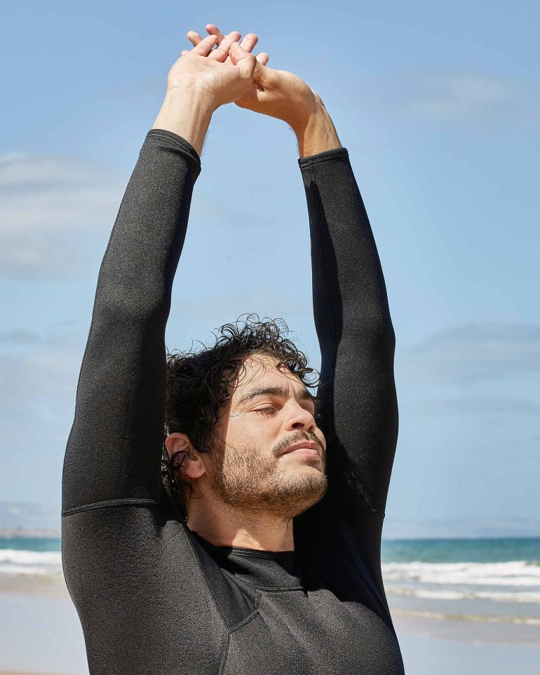 Model Nathan McGuire stretches on the beach, South Australia menswear editorial, Australia