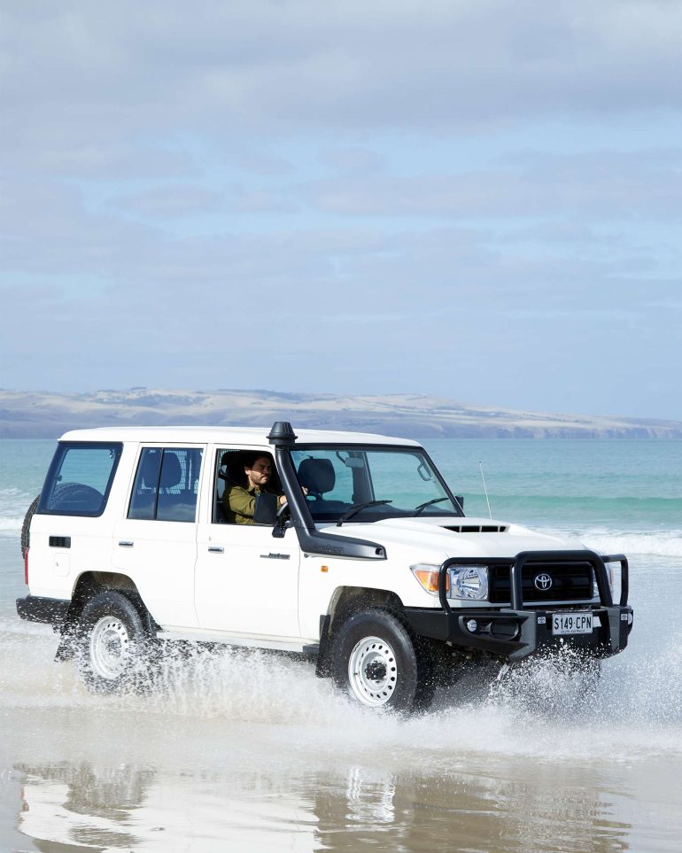 Model Nathan McGuire driving a Toyota Landcruiser on a beach, South Australia menswear editorial, Australia