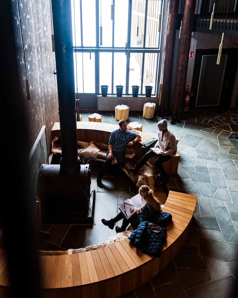 Guests spend time by a fireplace at Niehku Mountain Villa, Riksgränsen, Sweden