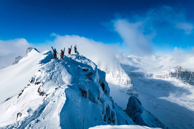 A group of heli-skiers atop a mountain in Swedish Lapland, Sweden