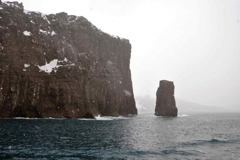 Rocks protrude from the sea at Deception Island, Antartica