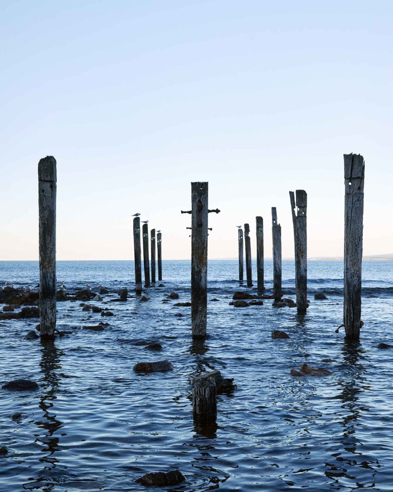 Poles half-submerged in the sea in Myponga Beach, Australia