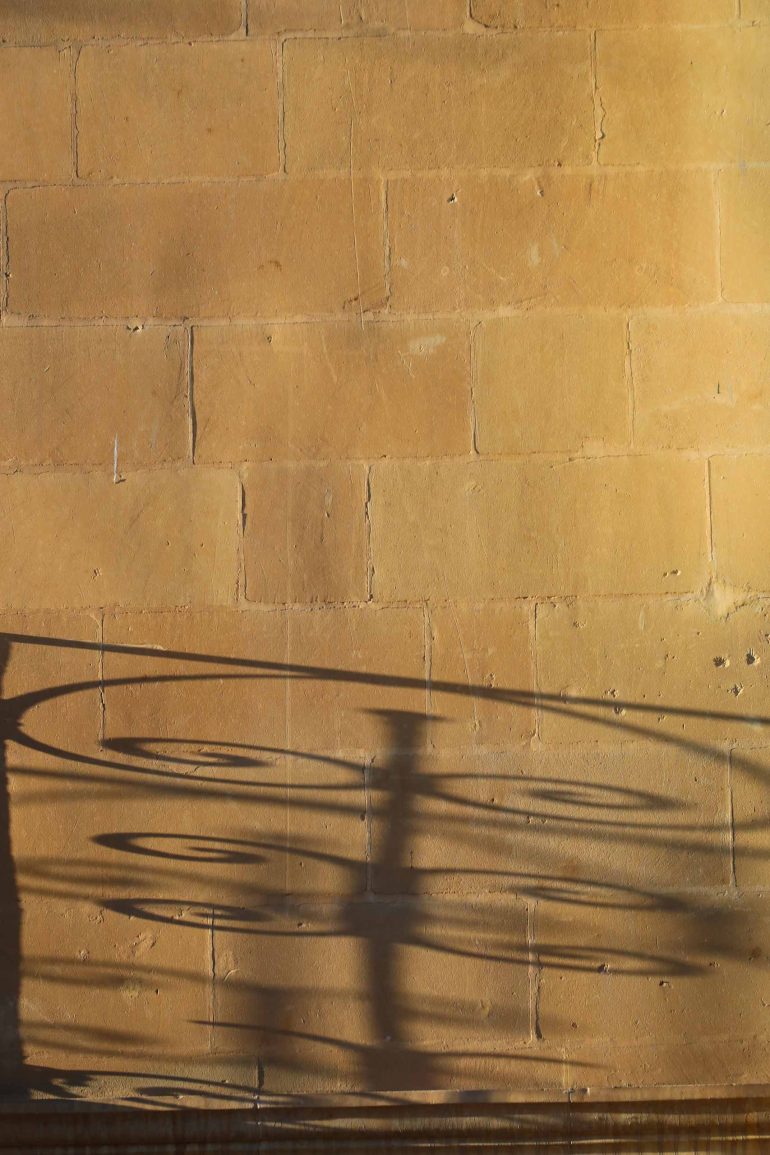 Close-up of a local yellow-ocher limestone wall with a decorative shadow cast upon it