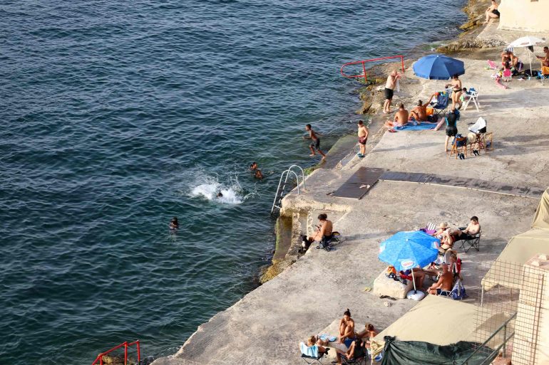Locals bask in the sun with the Mediterranean sea in front of them