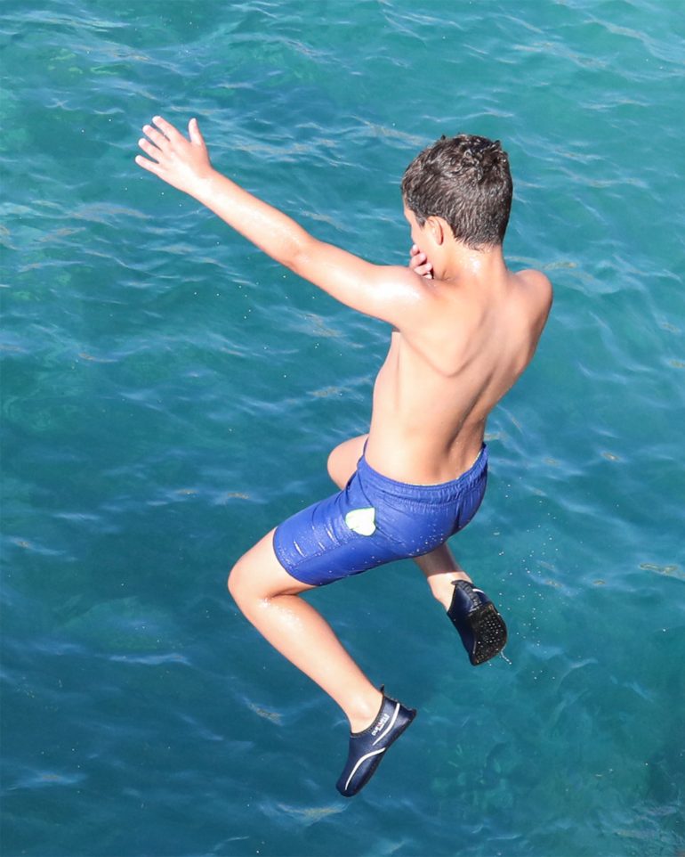 A young boy jumps into the ocean surrounding Malta