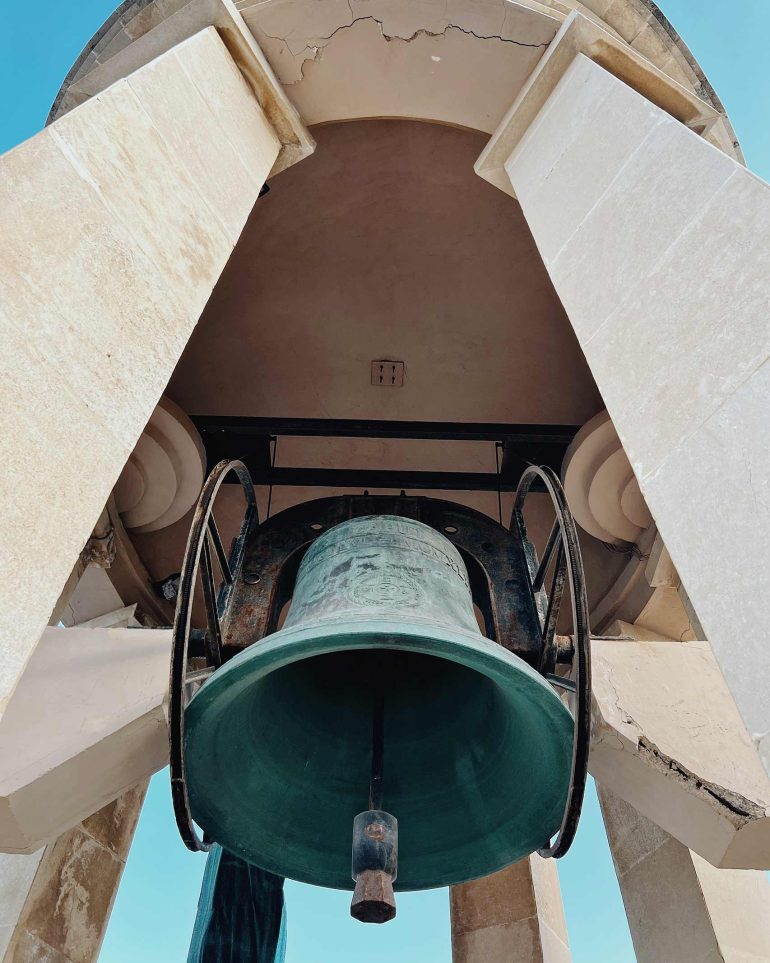 A large teal bell in a tower