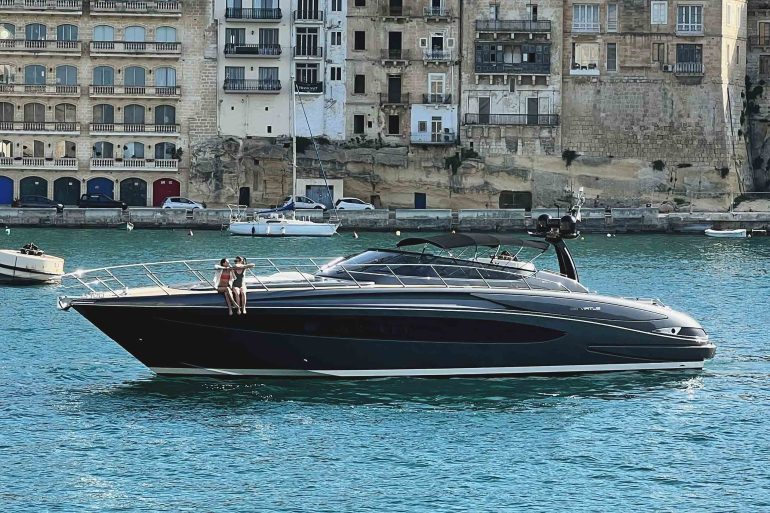 A yacht drifting in the sea before a Maltese town