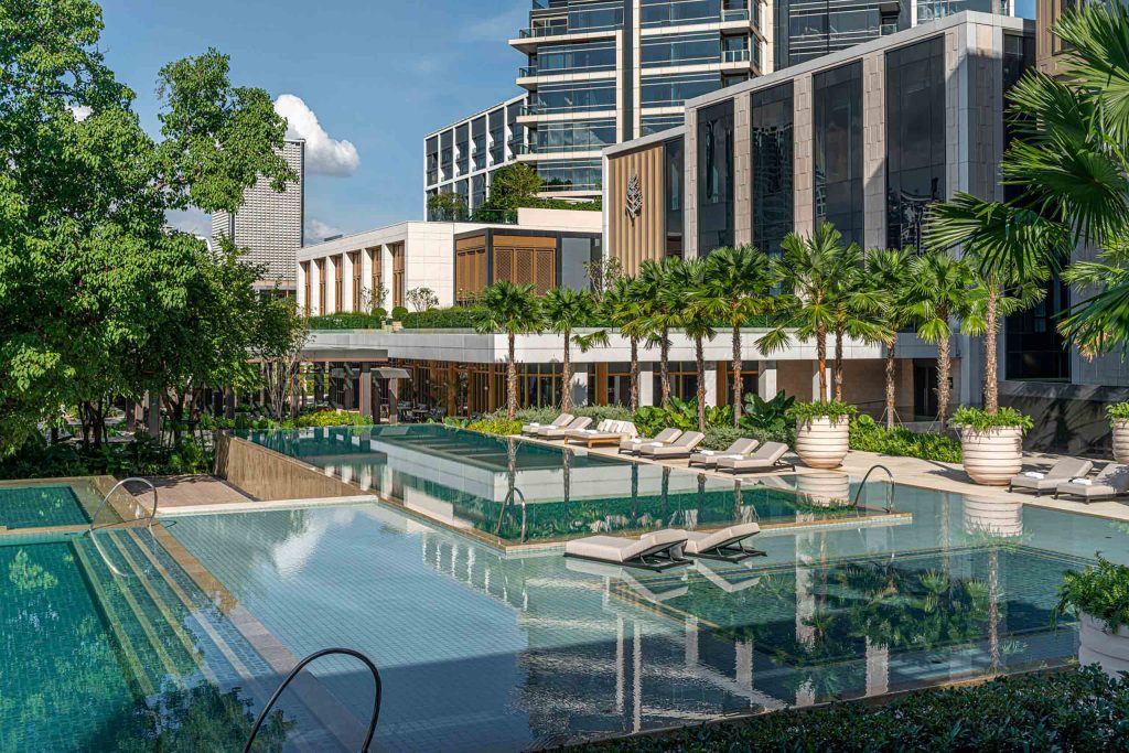 A pool with sun-loungers and tropical plants at the Four Seasons Bangkok at Chao Phraya River, Bangkok, Thailand