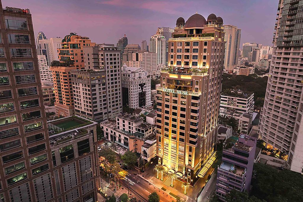 External view of the towering Hotel Muse Bangkok Langsuan – MGallery Collection against the city skyline
