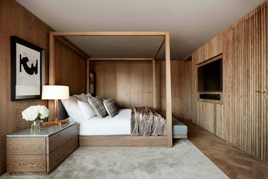 A bedroom with a blonde wooden frame to match the walls at Kimpton Blythswood Square, Glasgow, Scotland.