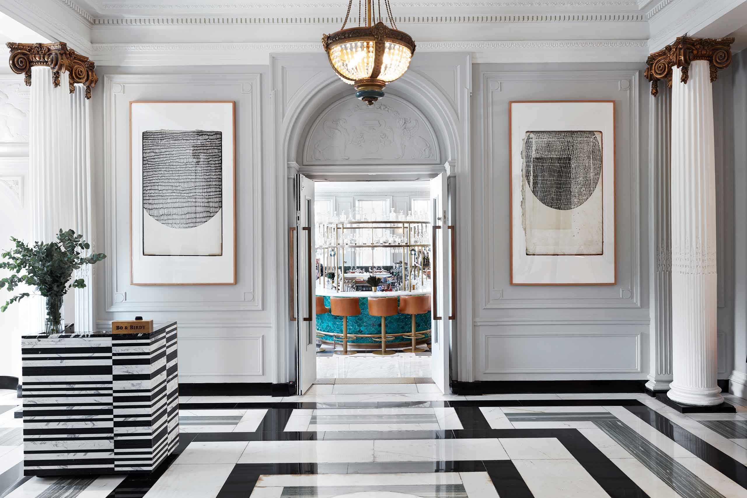 A foyer with a monochromatic tiled floor leading to a bar at Kimpton Blythswood Square, Glasgow, Scotland.