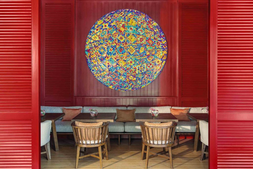 A breakfast table with a vibrant circular piece of art on the wall behind it