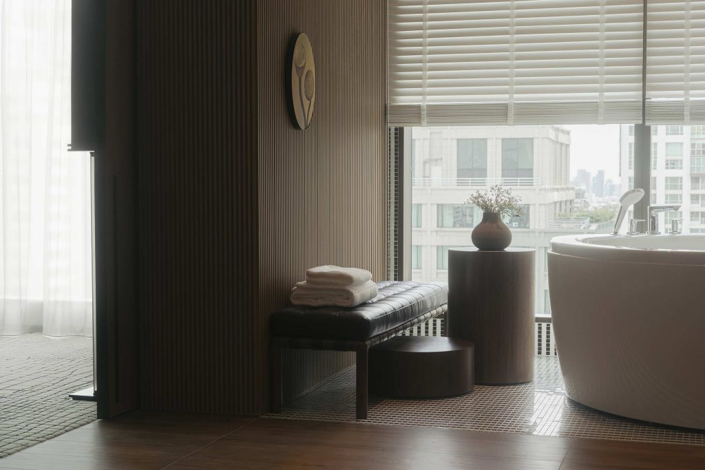 A dimly lit bathroom with a freestanding bathtub at Kimpton Maa-Lai Bangkok, Bangkok, Thailand