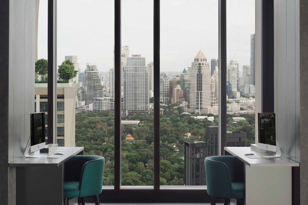 Two desks beside a window with panoramic views of Bangkok