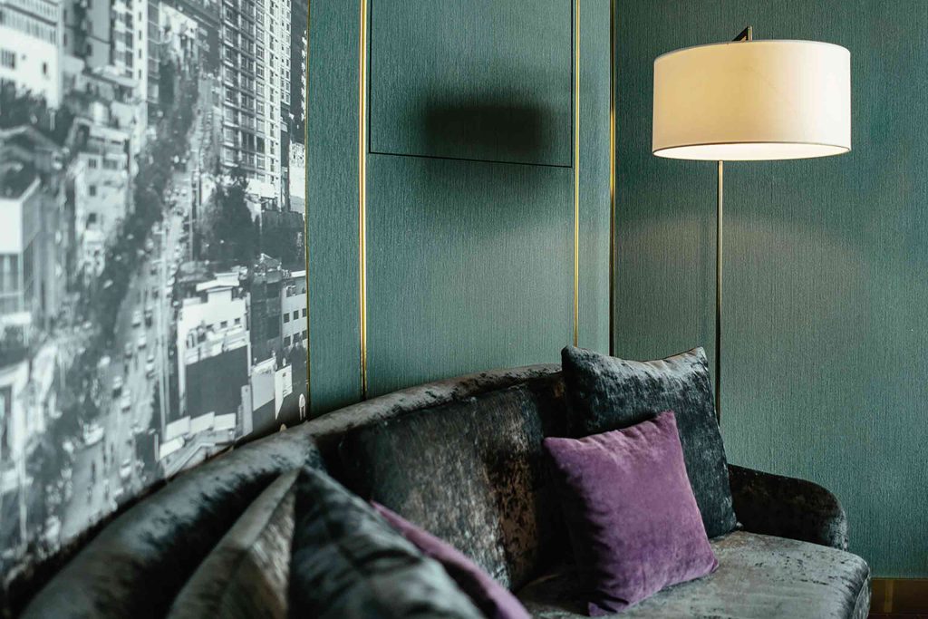 A dark green velvet couch with a black and white picture on the wall behind it.