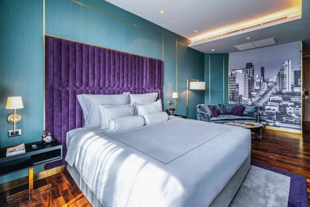 A stylish bedroom with teal walls at the MUU Bangkok.