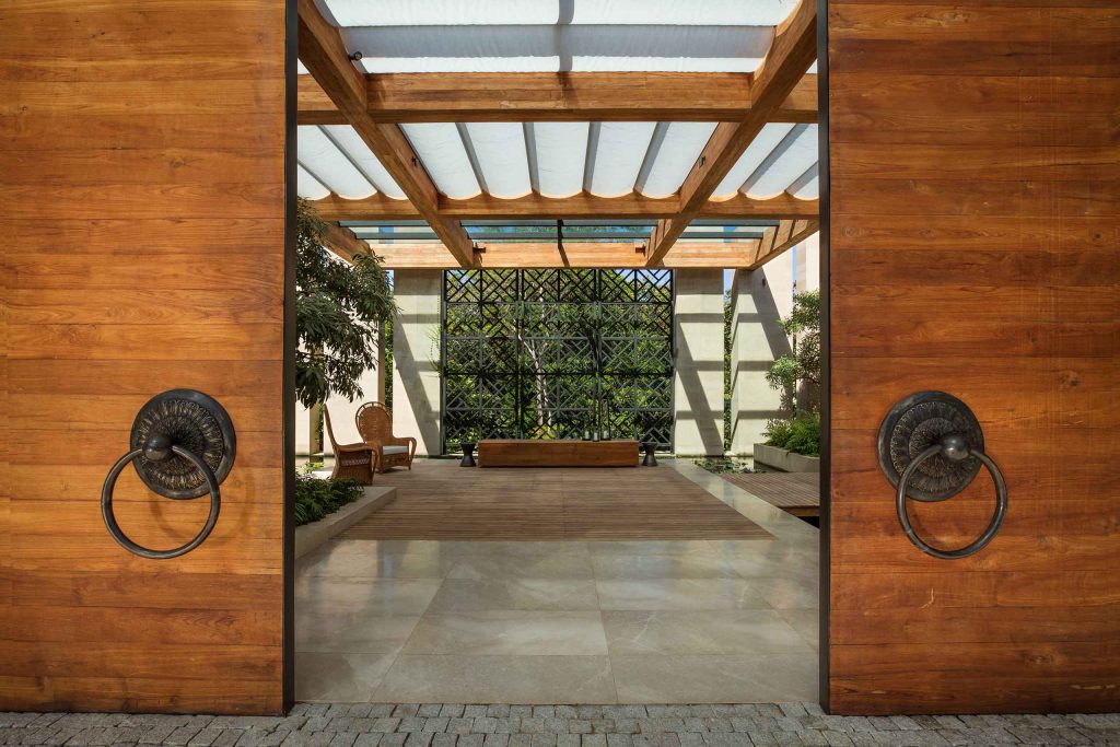 A theatrical entrance to the Rosewood Phuket with marble floors, plenty of natural light, and two majestic Thai doors.