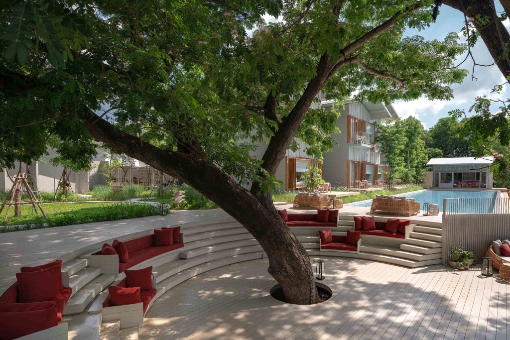 A plush green outdoor communal space surrounding a tree at Sala Bang Pa-In Ayutthaya, Thailand