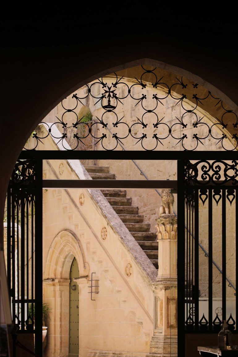 A intricately designed gate leading to a narrow street in Mdina