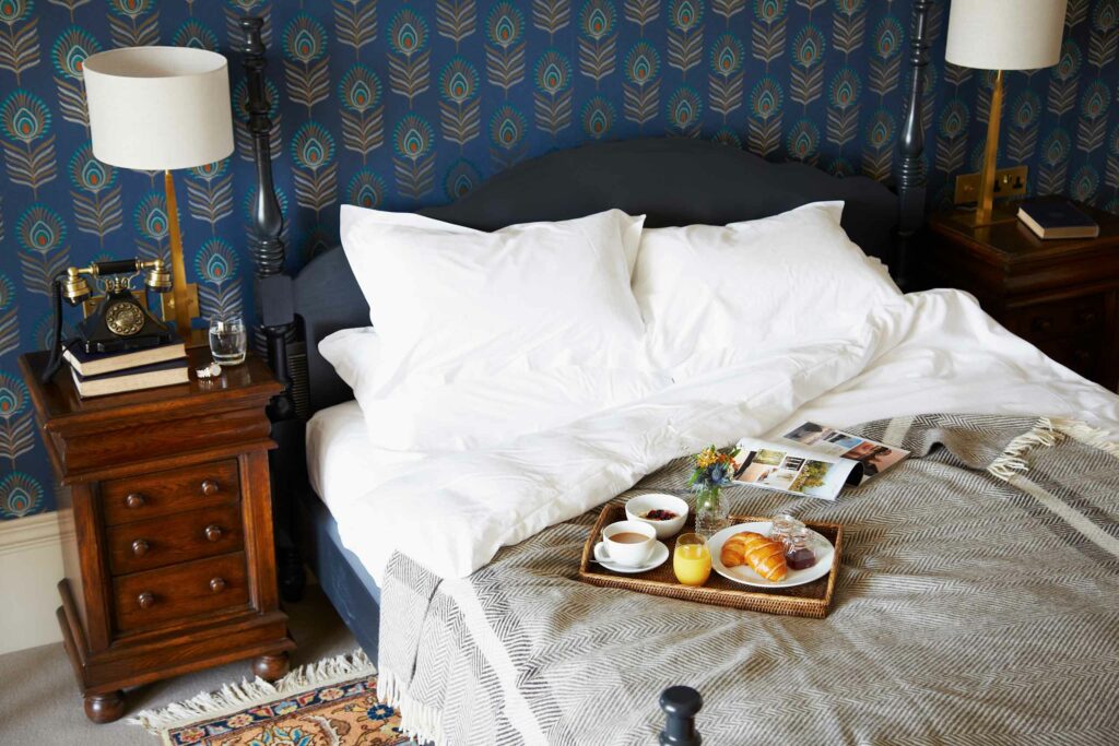 A bed with a tray of breakfast at The Roseate, Edinburgh. Stay during the The Edinburgh Festival Fringe.
