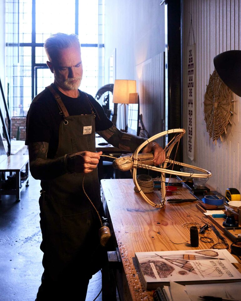 Dax Savage creating a woven basket in his workshop.