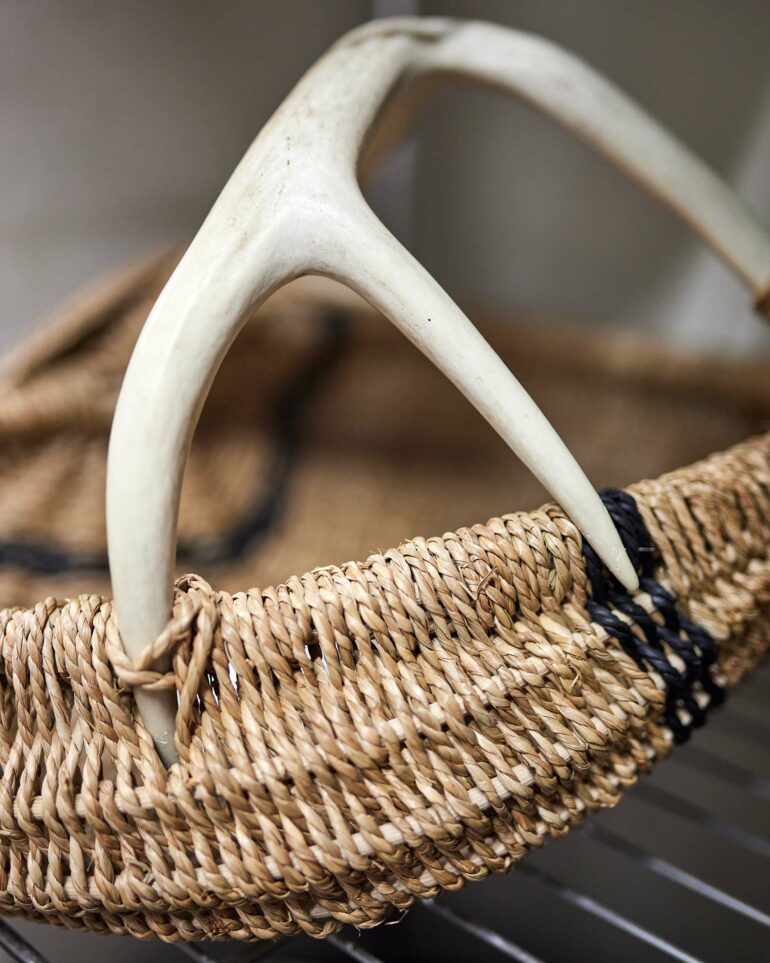 A woven basket with an antler for a handle.