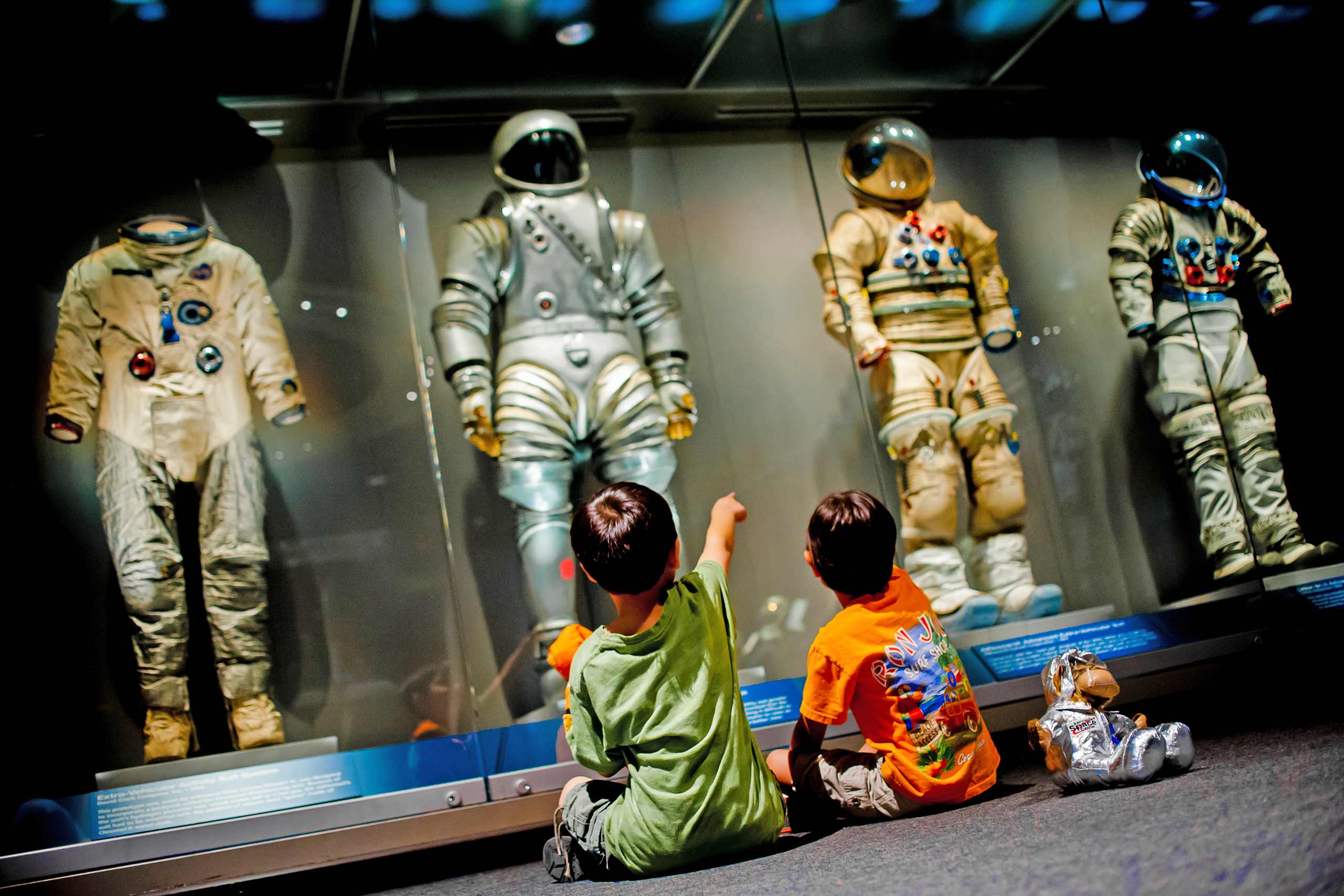 Two young boys admiring space suits on display.