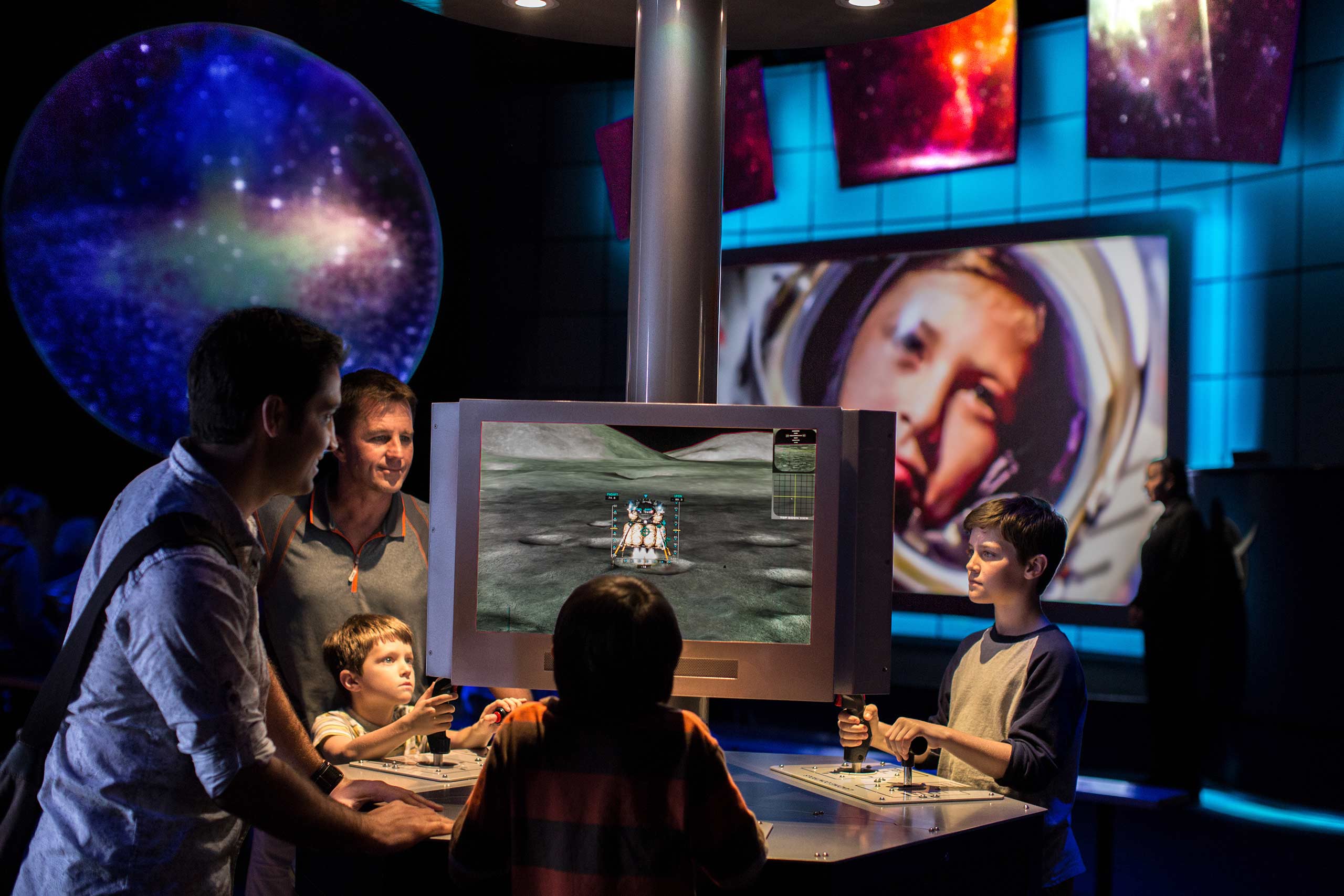 A family surrounding an interactive virtual game at the Kennedy Space Center.