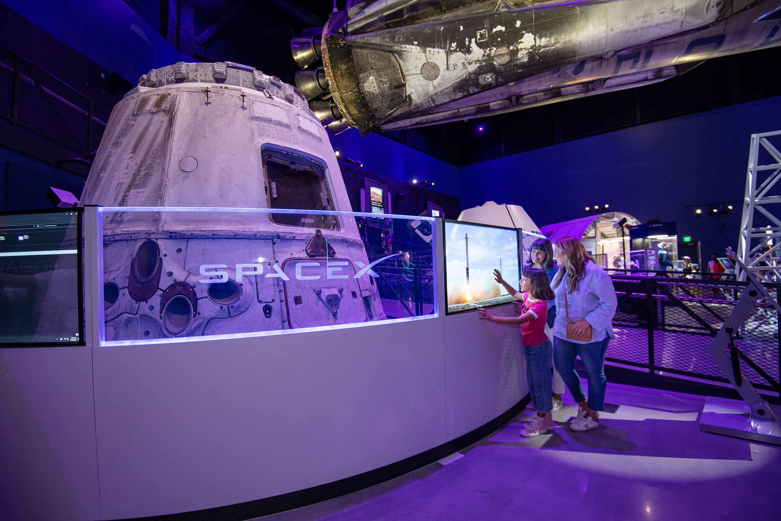 A little girl and her parents observing an interactive display at the Kennedy Space Center.