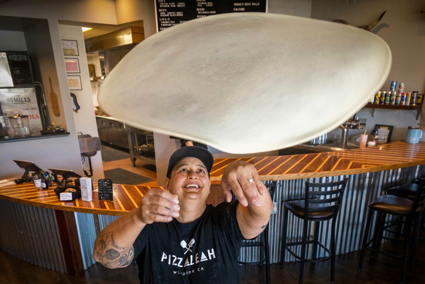 A chef tossing pizza dough at LeahPizza restaurant.