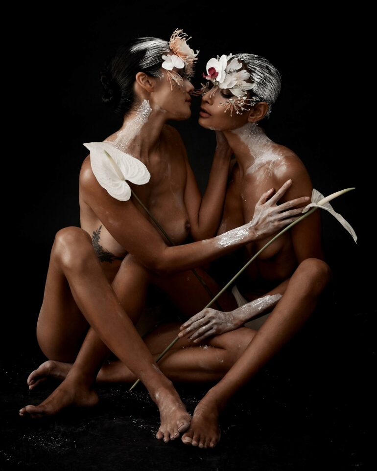 A picture of two nude subjects embellished in flowers.