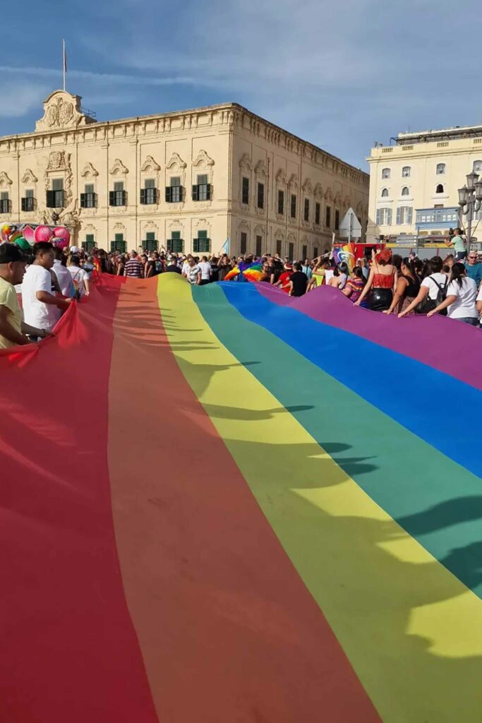 Revellers in Malta holding a huge rainbow flag.