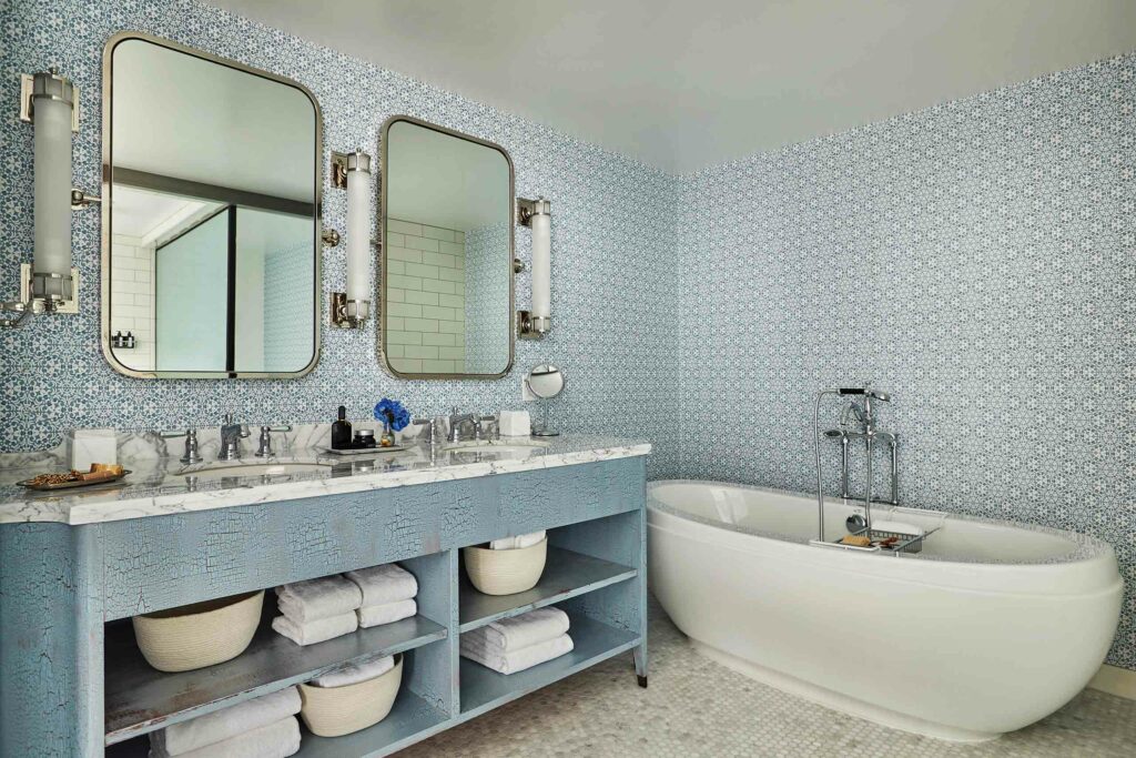 A bathroom with a freestanding bathtub and pale blue tiles.